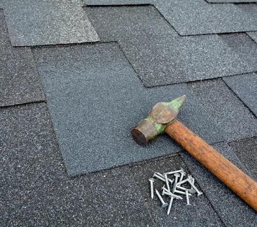 Roofing hammer resting on a course of asphalt shingles